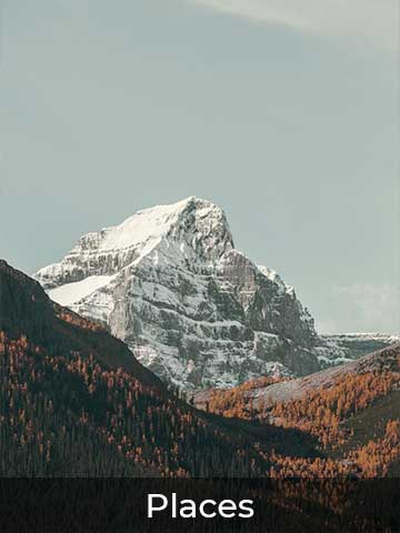 Majestic mountain landscape featuring a snow-capped peak surrounded by forested hills with warm autumn tones